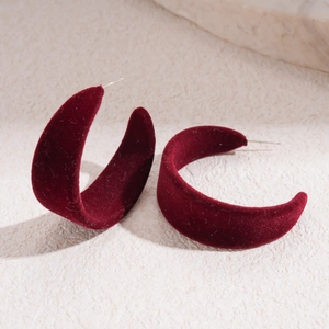 Detail of burgundy flocked C-shaped earrings with velvet texture and silver needles