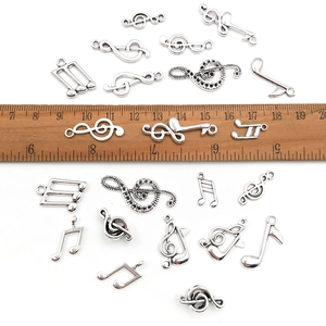 Collection of silver musical note charms with a wooden ruler to show small sizes