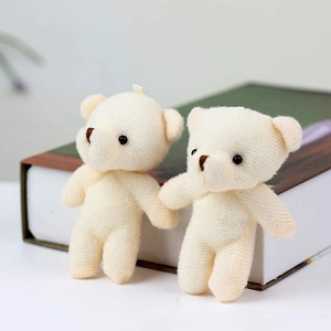 Pareja de mini ositos de peluche beige apoyados en un libro para decoración