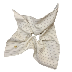 Striped fabric scrunchie in beige and gray with a decorative golden logo emblem