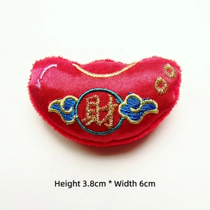 Close-up of red satin gold ingot charm with gold Cai embroidery and blue clouds