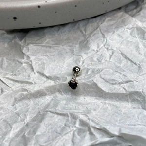 Macro shot of black heart-shaped zircon earring with silver beaded edge detailing