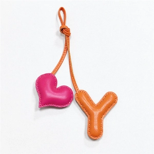 Close-up of pink heart and orange letter Y leather bag charms with stitching details