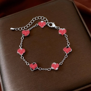 Close-up of silver chain bracelet with seven red heart pendants and lobster clasp