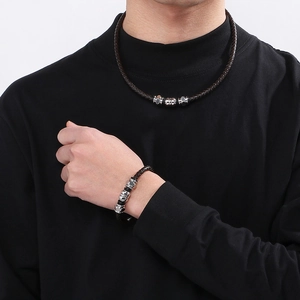 Close-up of men's braided leather bracelet and necklace set with silver beads