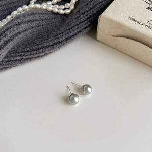 Close-up of grey pearl stud earrings with metallic luster on silver needle posts