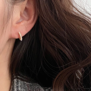 Gros plan de boucles d'oreilles créoles dorées avec perles blanches sur un mannequin