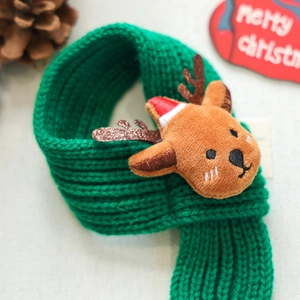 Detail of green knit Christmas pet scarf with a 3D plush reindeer doll and pine cone