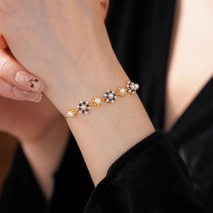 Macro detail of vintage gold flower bracelet with white pearls and deep blue gemstones