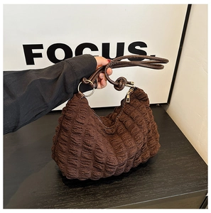 Close-up of deep brown quilted bubble texture handbag with minimalist leather handles