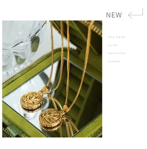 Detailed macro of vintage gold round floral embossed pendant in a velvet box