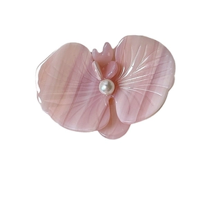 Pink orchid flower hair clip with marble texture and pearl detail on white background