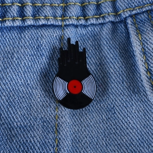 Macro shot of creative vinyl record brooch with red center on blue denim fabric
