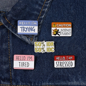 Detail of five creative enamel word pins on a blue denim jacket for accessory styling