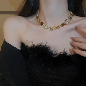 Macro shot of gold-toned geometric necklace with amber and yellow-brown square-cut crystals
