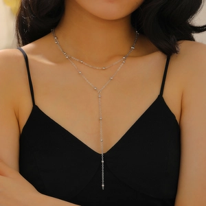 Detail of silver double layer Y-necklace with small beads on a female model in black dress