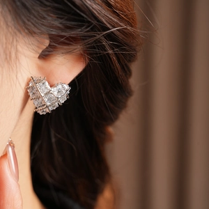 Gros plan de boucles d'oreilles cœur en argent avec zircon carré portées par un mannequin