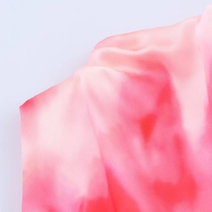 Detalle macro de la textura de satén con degradado rosa y rojo en este vestido midi