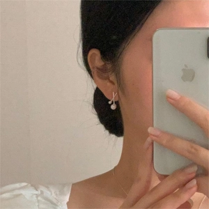 Close-up of minimalist 925 sterling silver pearl earrings worn in a stylish selfie