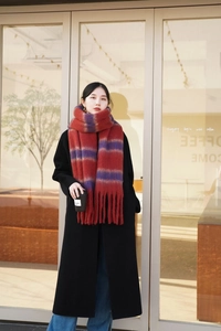 Close-up of thick striped knit scarf with long tassels paired with a black winter coat