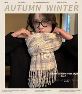 Detail of grey checked knit scarf with colorful specks and decorative long tassels
