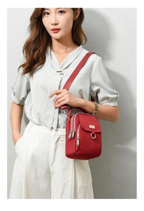 Detailed view of red nylon crossbody bag with multiple zip pockets and wide strap