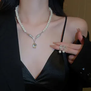 Elegant water drop pearl necklace and earring set on model with diamond wing detail