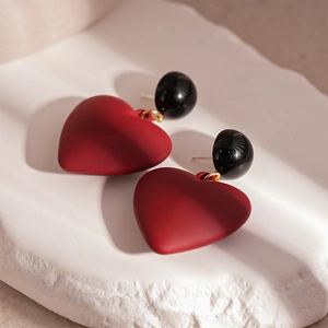 Detail shot of vintage red heart earrings with black bead studs on a textured stone base