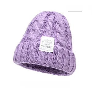 Close-up of purple cable knit texture and white textile label on a winter beanie