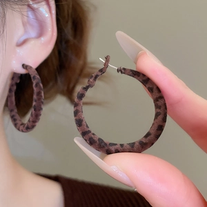Gros plan de boucles d'oreilles créoles léopard avec flocage et motif vintage marron