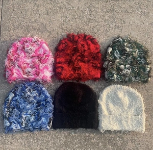 Flat lay of six knit beanies with distressed fringe details in various color patterns