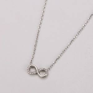 Détail d'un pendentif signe infini serti de zircons blancs sur une chaîne en argent fin