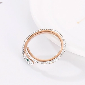 Close-up of rose gold snake ring with white pave crystals and green gemstone eyes