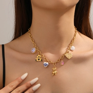 Close-up of gold chain necklace with colorful bear charms and blue floral heart pendants