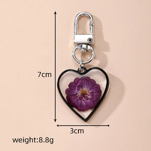 Detail view of heart-shaped keychain with purple dried flower and silver metal lobster clasp