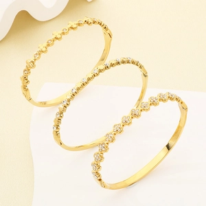 Close-up of gold clover bracelets set with sparkling white zircon stones for women