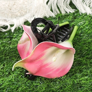 Close-up of a pink calla lily hair claw clip with black base on green grass