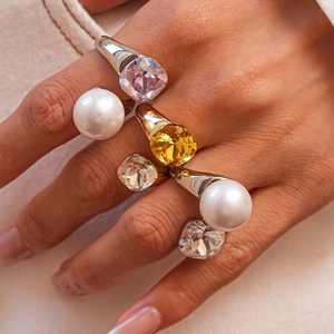 Macro shot of stacked rings featuring colorful crystals and large white pearls