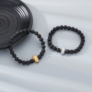 Detailed macro view of 8mm black lava stone beads and metallic Buddha head charms