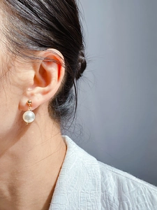 Close-up of elegant pearl drop earring with golden stud on model for a minimalist look