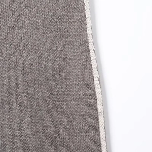 Detailed close-up of dark grey knit fabric texture with cream contrast trim edges