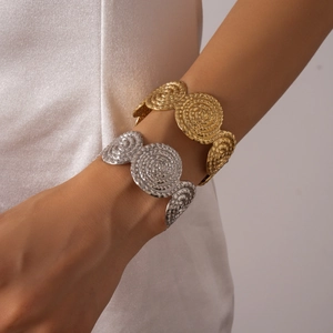 Détail d'un large bracelet spirale en métal texturé avec finitions or et argent