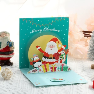 3D pop-up Christmas card featuring Santa Claus, penguin, and tree with Merry Christmas text
