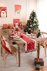 Close-up of red Christmas table runner with white reindeer patterns and tassel detail