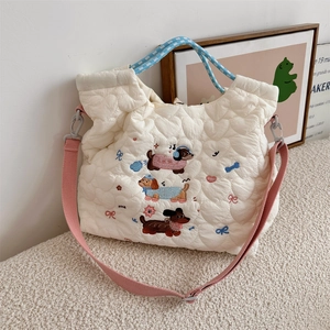 Detail of white quilted tote bag featuring cute cartoon dachshund embroidery and pink strap