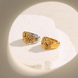 Detailed macro view of 18K gold plated flower rings on a textured white stone base