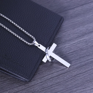 Macro shot of silver titanium steel cross and ring pendant on a sleek chain