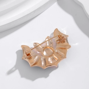 Back view of gold bat brooch showing the safety pin fastener and textured finish