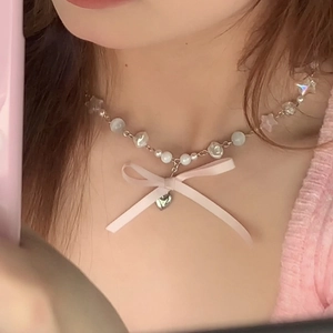 Collier en perles avec nœud rose, pendentif cœur et perles étoiles porté par un modèle