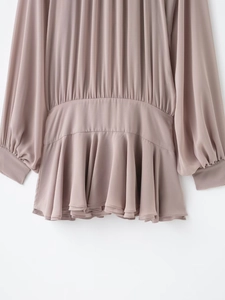 Close-up of ruffled hem and pleated waist details on a dusty pink chiffon dress